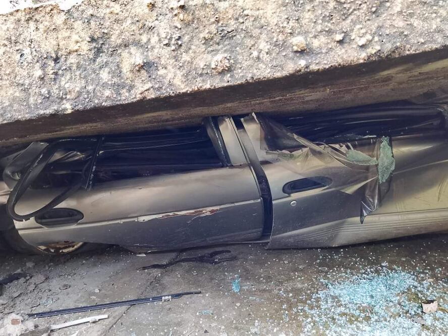 Un vehículo Nissan tipo Tsuru de color gris quedó debajo de la barda. Foto Especial